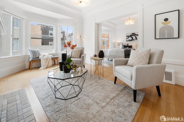 sitting room with baseboards, wood finished floors, visible vents, and crown molding