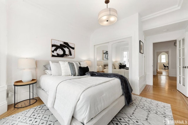 bedroom with french doors, light wood finished floors, and a closet