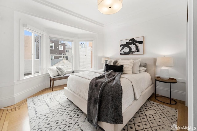 bedroom featuring light wood finished floors and baseboards