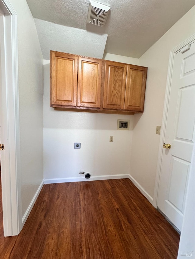 washroom with electric dryer hookup, hookup for a washing machine, dark hardwood / wood-style floors, cabinets, and a textured ceiling