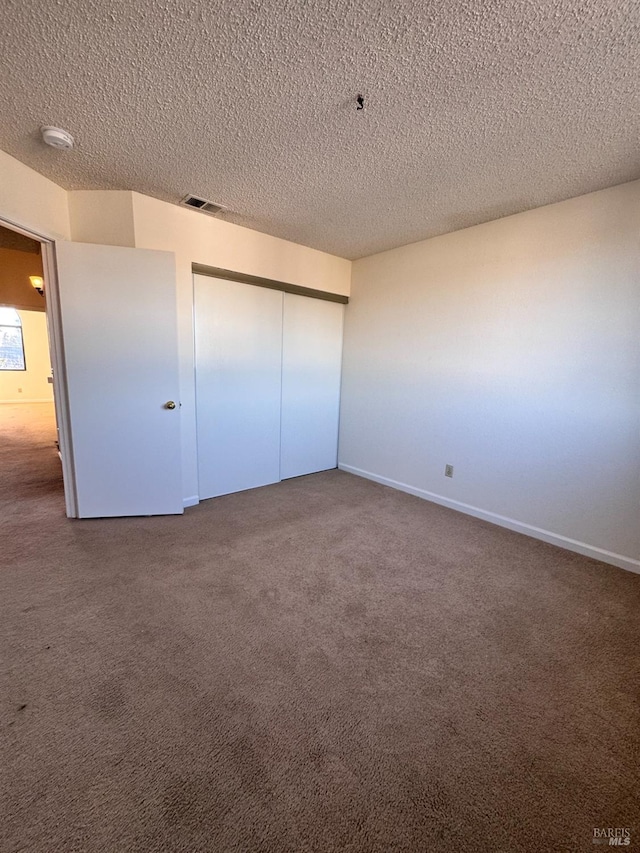 unfurnished bedroom with a closet, a textured ceiling, and carpet