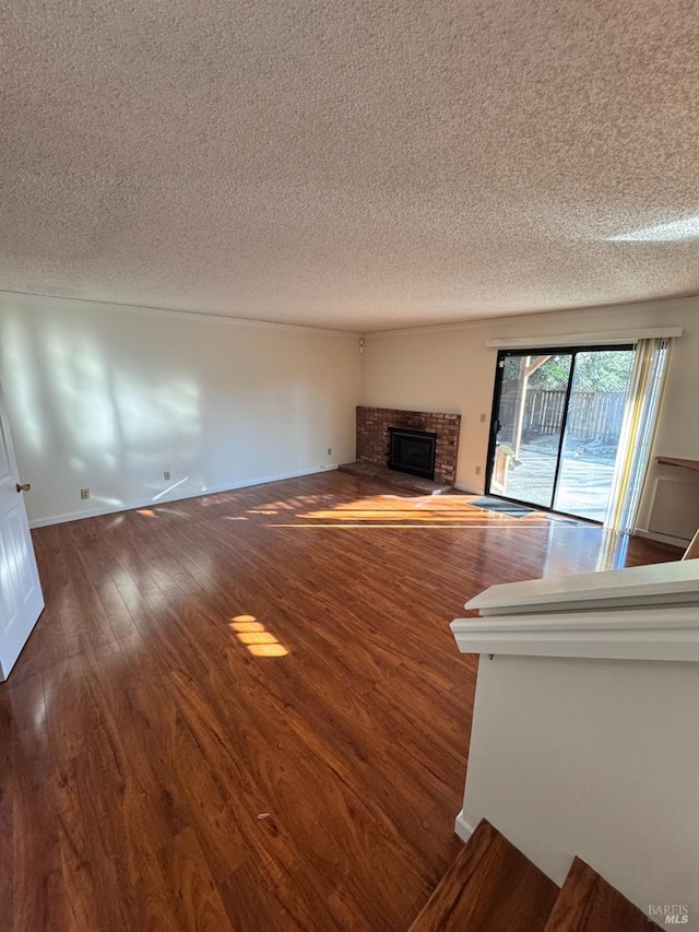 unfurnished living room with a fireplace, dark hardwood / wood-style floors, and a textured ceiling