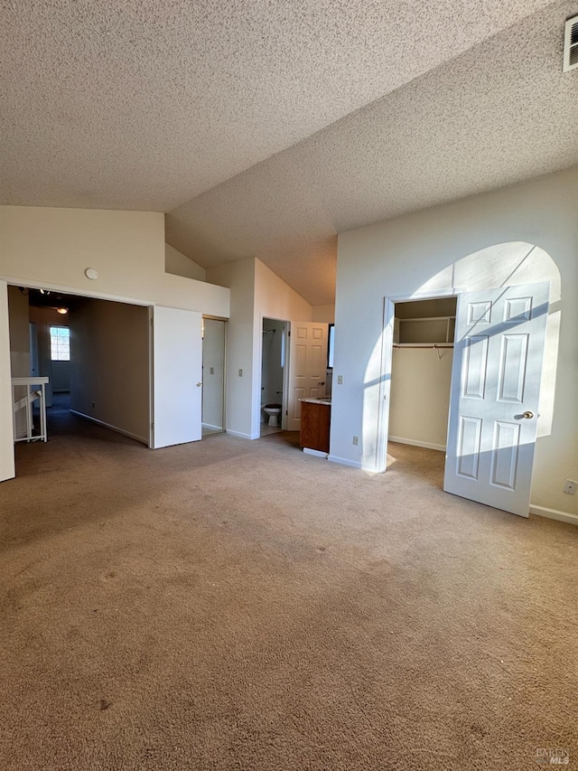 unfurnished living room with vaulted ceiling, carpet, and a textured ceiling