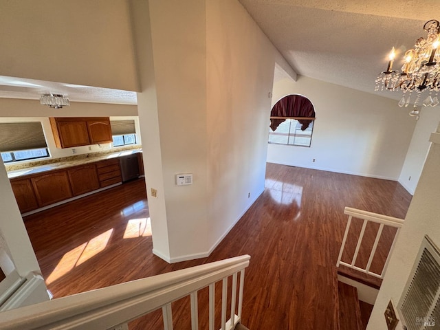 hallway featuring vaulted ceiling with beams, an inviting chandelier, a textured ceiling, plenty of natural light, and dark hardwood / wood-style floors