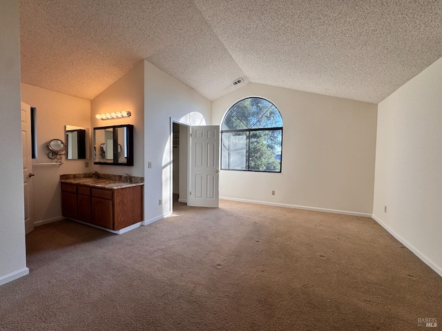 unfurnished bedroom with lofted ceiling, sink, carpet floors, and a textured ceiling