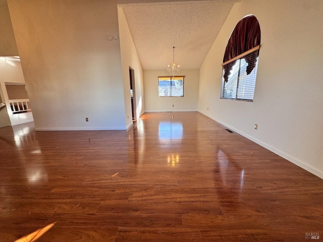 empty room featuring an inviting chandelier, dark hardwood / wood-style flooring, and a textured ceiling