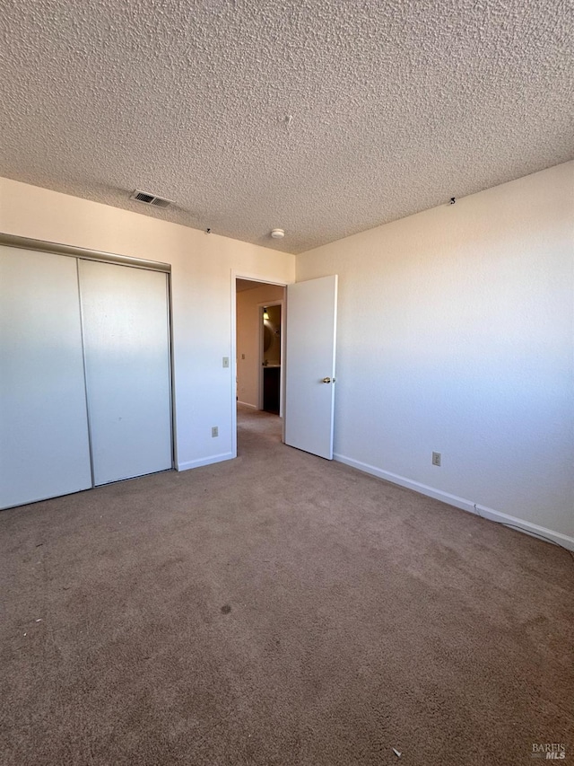 unfurnished bedroom with carpet, a textured ceiling, and a closet