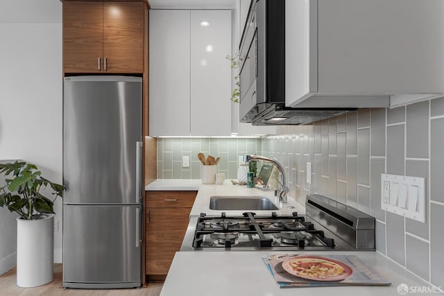 kitchen featuring sink, decorative backsplash, stainless steel refrigerator, and range