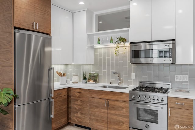 kitchen with white cabinetry, stainless steel appliances, sink, and decorative backsplash