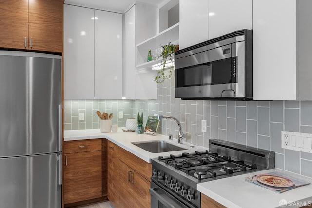 kitchen featuring white cabinetry, appliances with stainless steel finishes, sink, and decorative backsplash