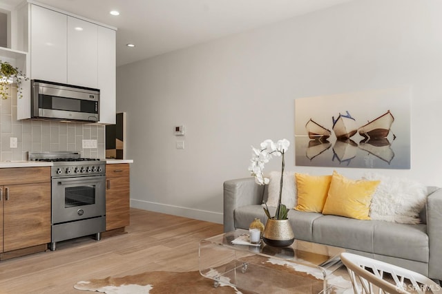 kitchen with white cabinetry, backsplash, light hardwood / wood-style floors, and appliances with stainless steel finishes