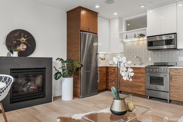 kitchen with white cabinetry, backsplash, and stainless steel appliances