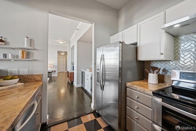 kitchen featuring backsplash, white cabinets, light stone counters, wall chimney range hood, and stainless steel appliances