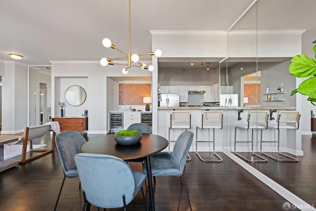 dining room with dark wood-type flooring, beverage cooler, crown molding, and an inviting chandelier