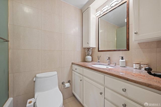 bathroom with vanity, toilet, tile walls, and tile patterned floors