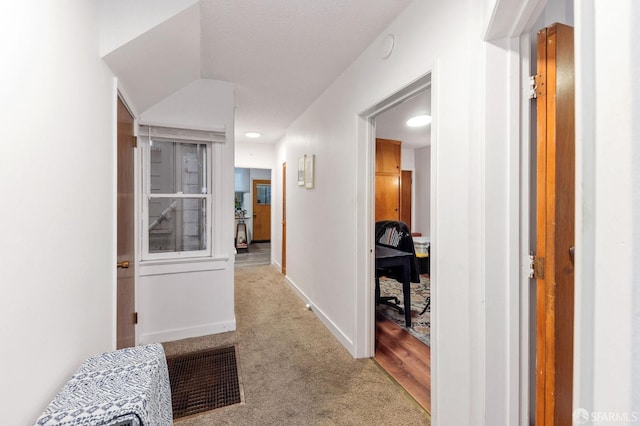 hallway featuring visible vents, baseboards, and carpet flooring