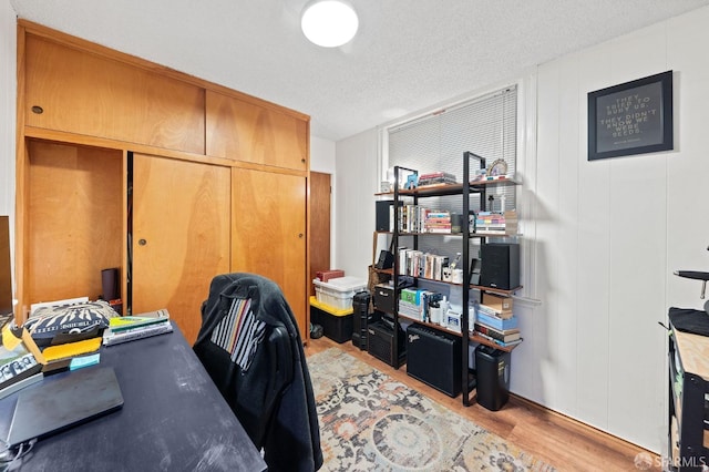 home office with a textured ceiling and light wood-style floors