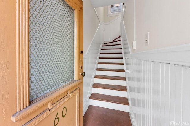 stairway with a wainscoted wall