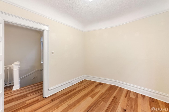 empty room with baseboards, light wood-style flooring, and a textured ceiling