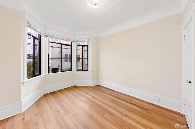 spare room featuring plenty of natural light, light wood-type flooring, and baseboards