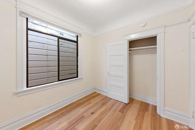 unfurnished bedroom with light wood-style flooring, a closet, baseboards, and a textured ceiling