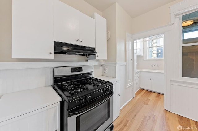 kitchen featuring light wood-style floors, light countertops, under cabinet range hood, white cabinetry, and stainless steel range with gas stovetop