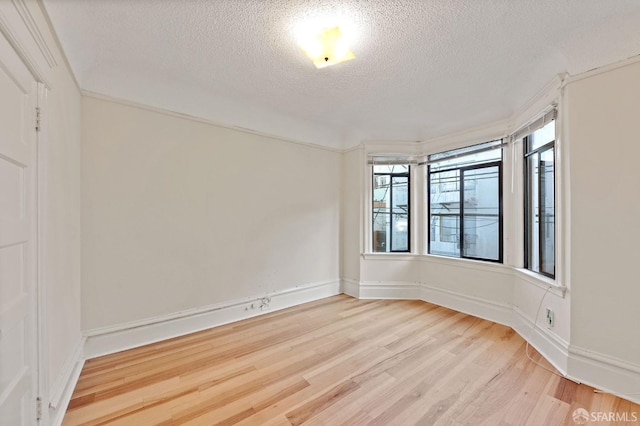 unfurnished room with light wood-style floors, a textured ceiling, and baseboards