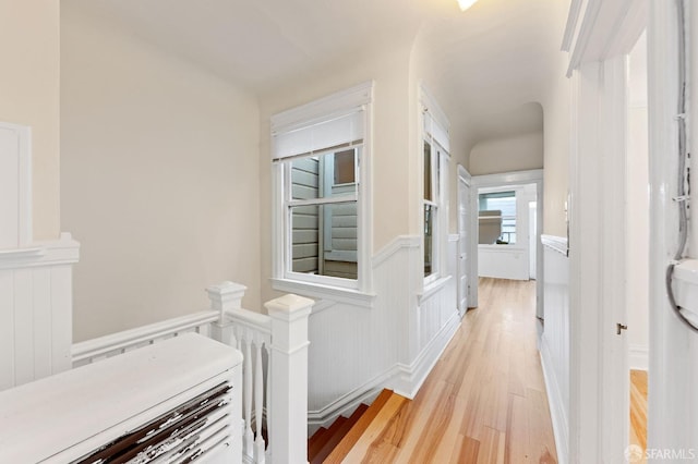 corridor with a wainscoted wall and light wood-style flooring