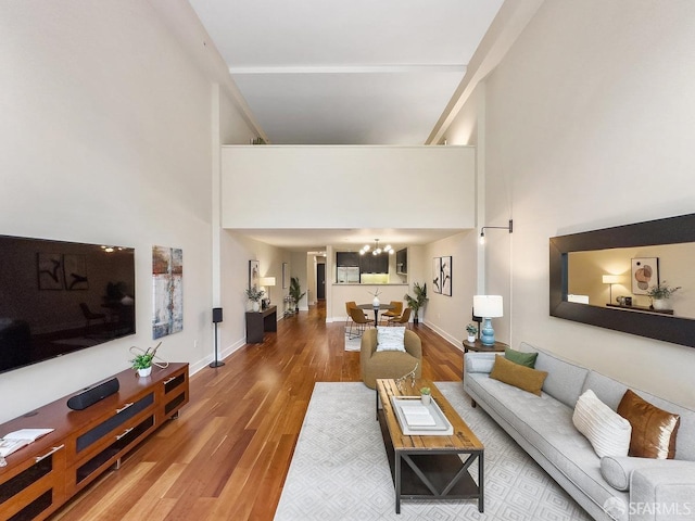 living room with wood-type flooring, a notable chandelier, and a high ceiling