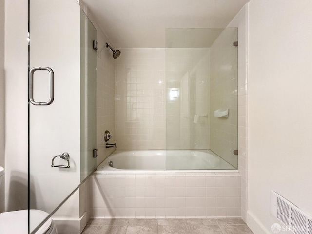 bathroom featuring bath / shower combo with glass door, tile patterned floors, and toilet