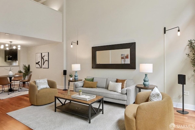 living room featuring an inviting chandelier, a towering ceiling, and hardwood / wood-style floors