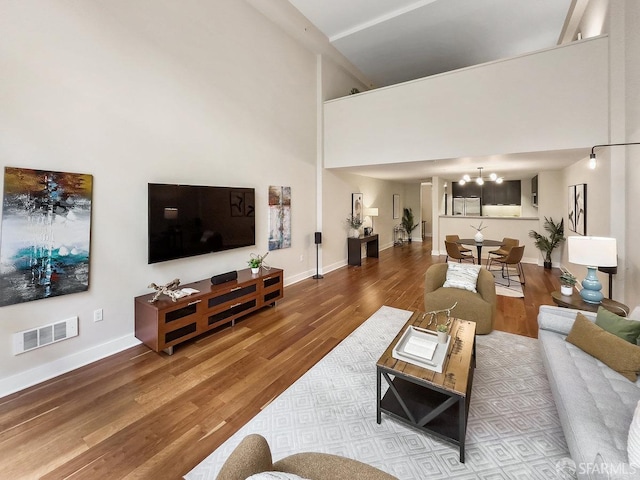 living room featuring a chandelier, hardwood / wood-style floors, and a high ceiling