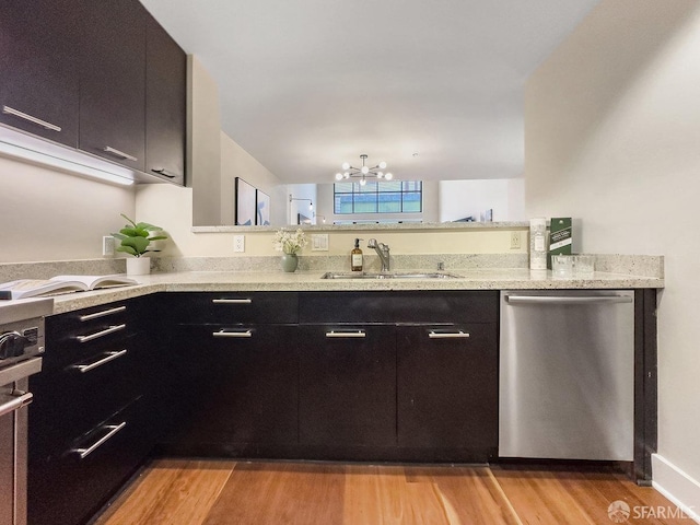 kitchen with light stone counters, sink, light hardwood / wood-style flooring, a chandelier, and dishwasher