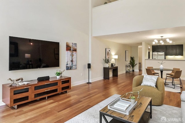 living room with an inviting chandelier, hardwood / wood-style flooring, and a high ceiling