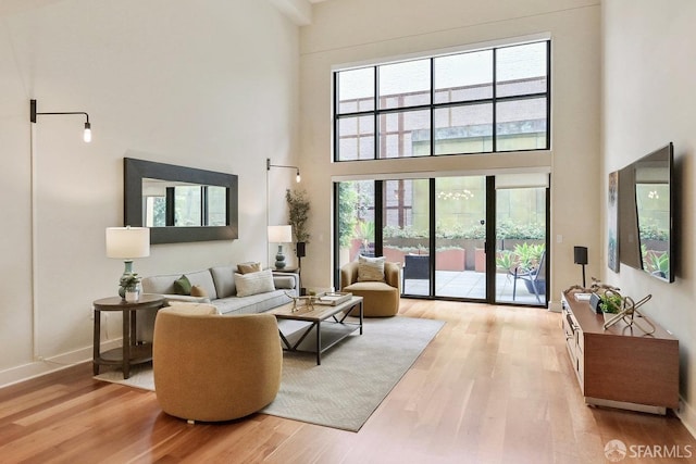 living room with light wood-type flooring and a high ceiling