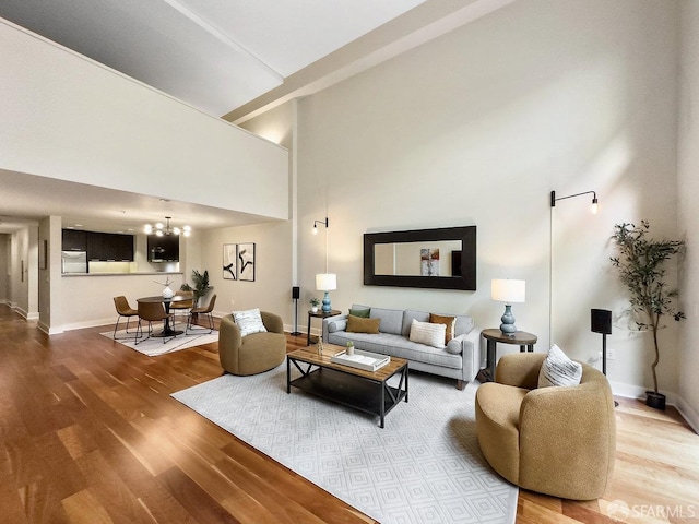 living room with wood-type flooring, a chandelier, and a high ceiling