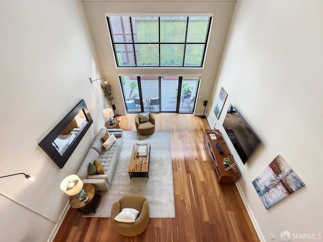 living room with a towering ceiling, hardwood / wood-style floors, and a healthy amount of sunlight