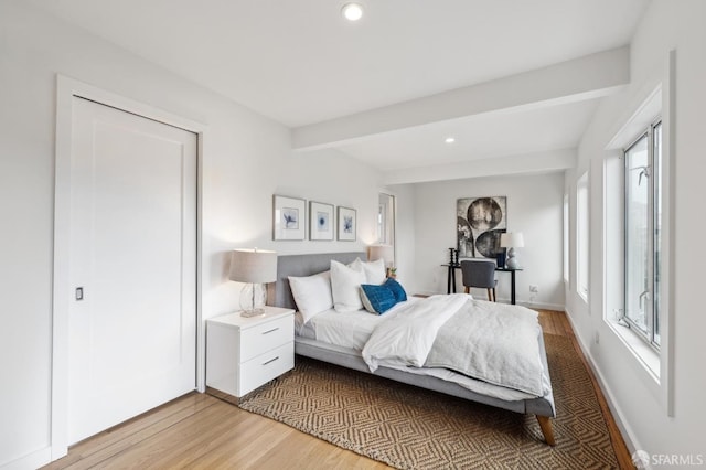 bedroom featuring beamed ceiling and light hardwood / wood-style floors