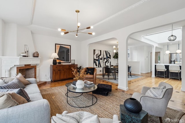 living room featuring a notable chandelier, a fireplace, and hardwood / wood-style floors