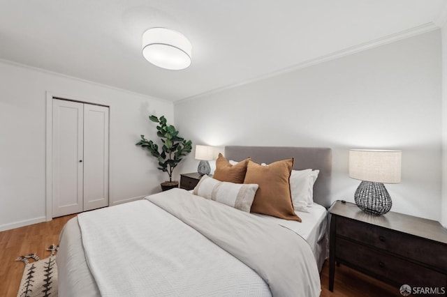 bedroom with crown molding, a closet, and light hardwood / wood-style flooring