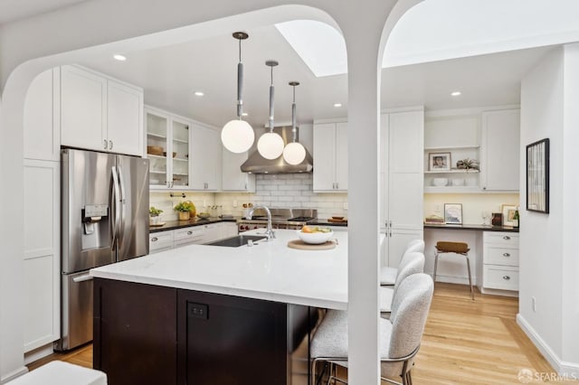 kitchen with pendant lighting, white cabinetry, an island with sink, sink, and stainless steel fridge with ice dispenser