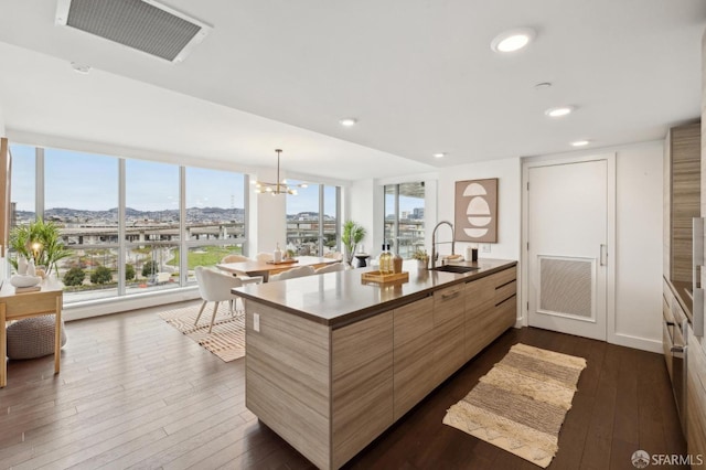 kitchen featuring sink, an inviting chandelier, hanging light fixtures, dark hardwood / wood-style floors, and a wall of windows