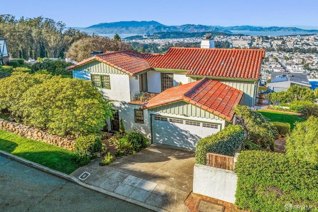 mediterranean / spanish-style home featuring a tiled roof, concrete driveway, stucco siding, and a chimney
