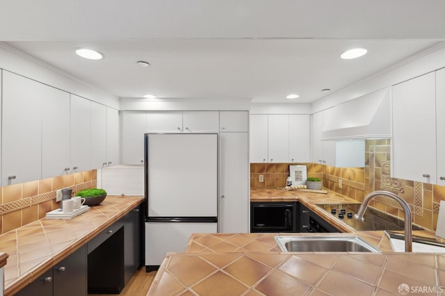 kitchen featuring white cabinetry, white refrigerator, and tile countertops