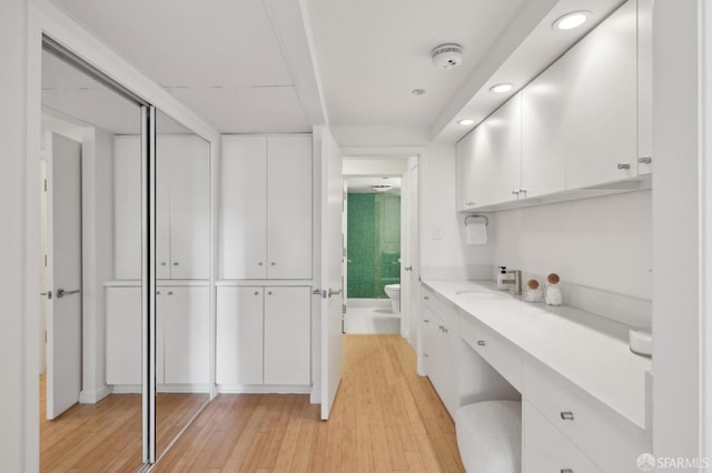 interior space with sink, light wood-type flooring, and white cabinetry