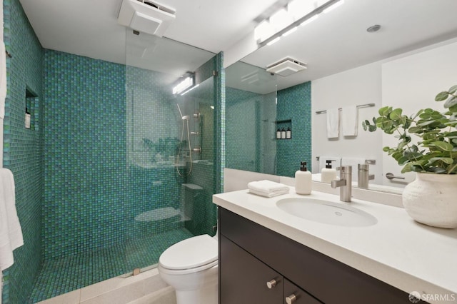 bathroom featuring vanity, toilet, tiled shower, and tile patterned floors