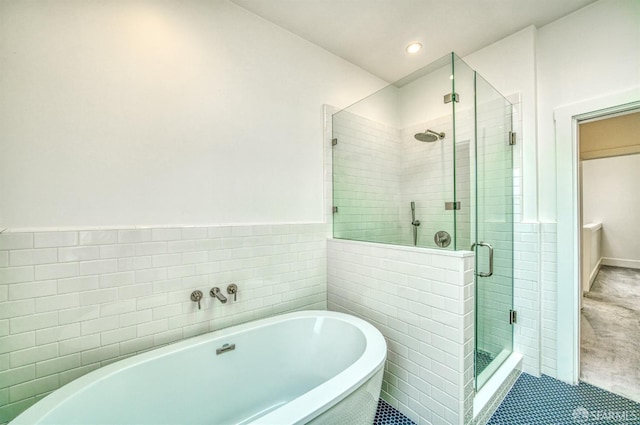 bathroom with tile patterned flooring, tile walls, and separate shower and tub