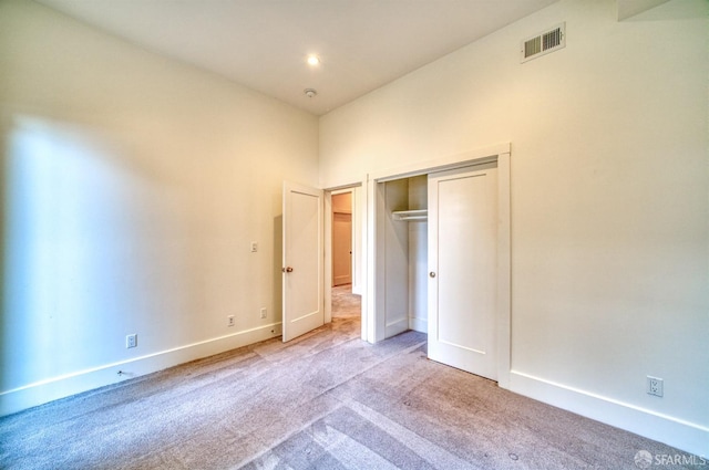 unfurnished bedroom with light colored carpet and a closet