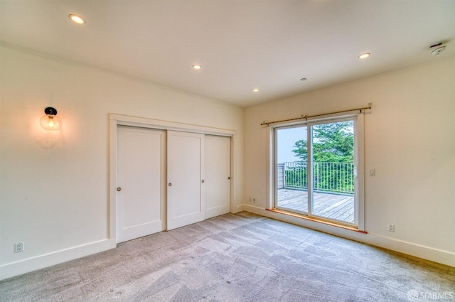 unfurnished bedroom featuring access to outside, a closet, and light carpet