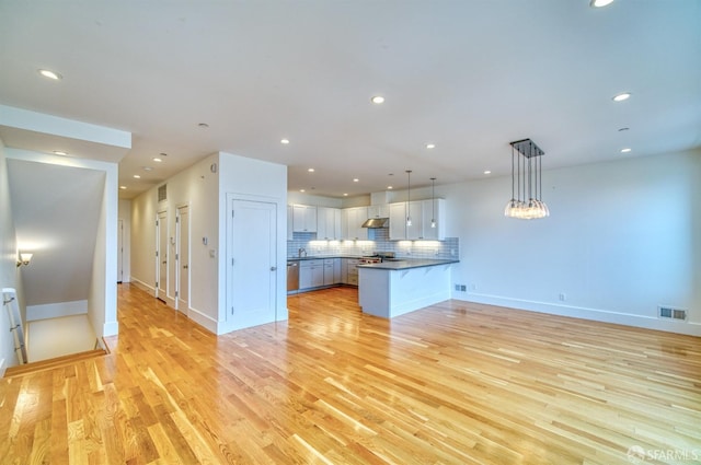 kitchen with kitchen peninsula, light hardwood / wood-style floors, pendant lighting, and white cabinetry